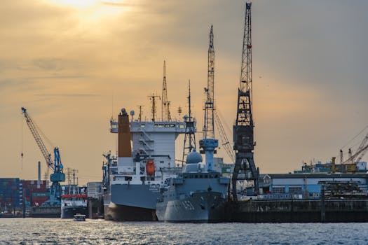 Cargo port scene with ships and cranes at sunset, showcasing industrial and maritime activity.